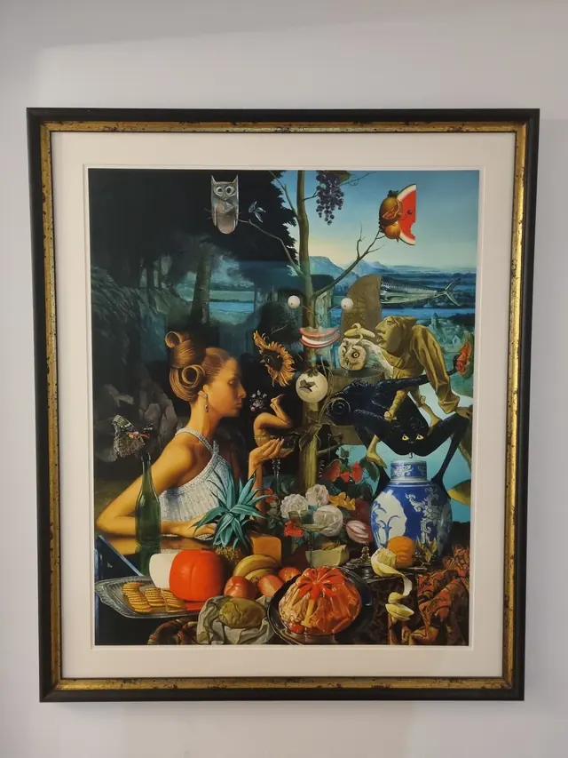 A surrealist still-life print in an ornate dark gold frame
