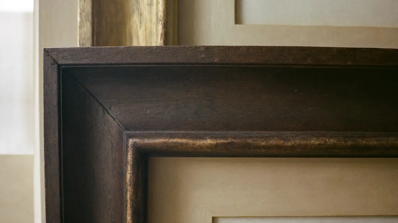 Close detail of dark timber and gilt frame mouldings